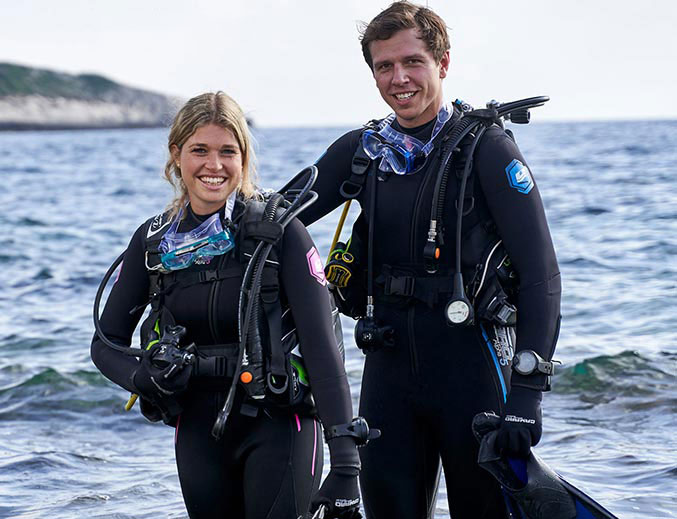 Man and woman dive with Alpha 5mm Pro Overall Camaro suits