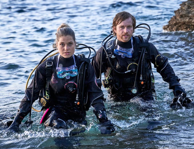 Mann und Frau kommen aus dem Wasser und tragen Drytec Lite 3.0 Anzüge von Camaro